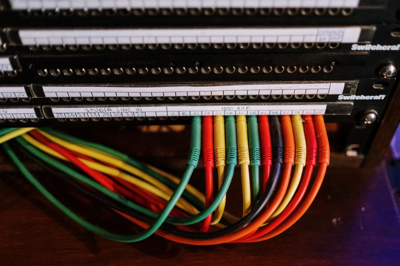 Colored audio cables connected to a labeled patch panel