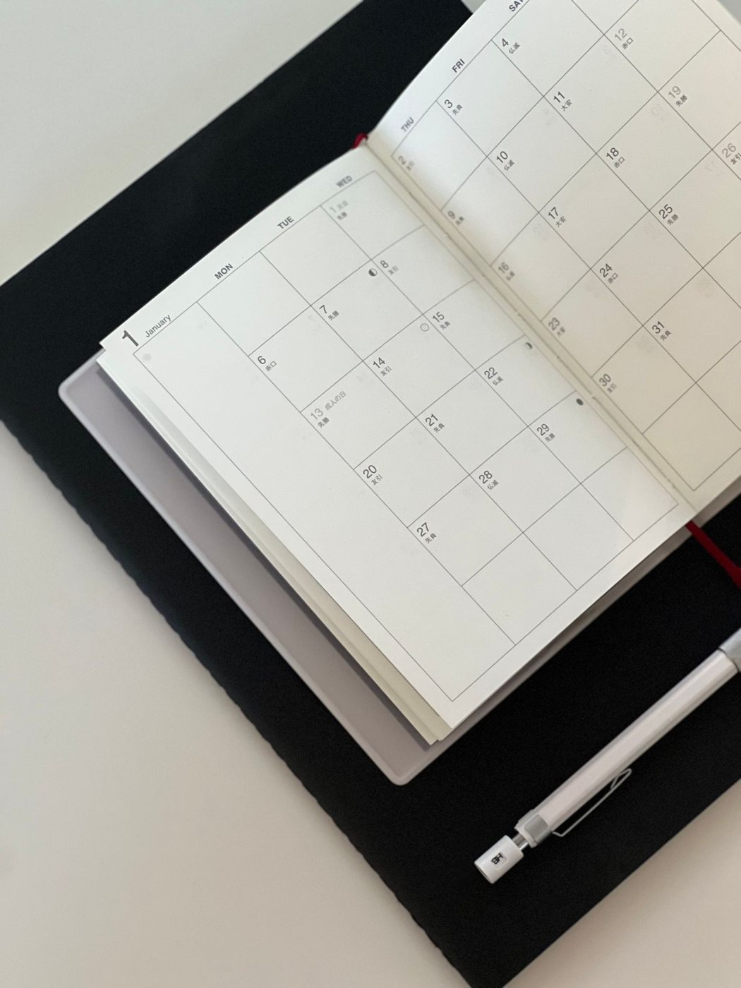 Open calendar planner beside a pen and tablet