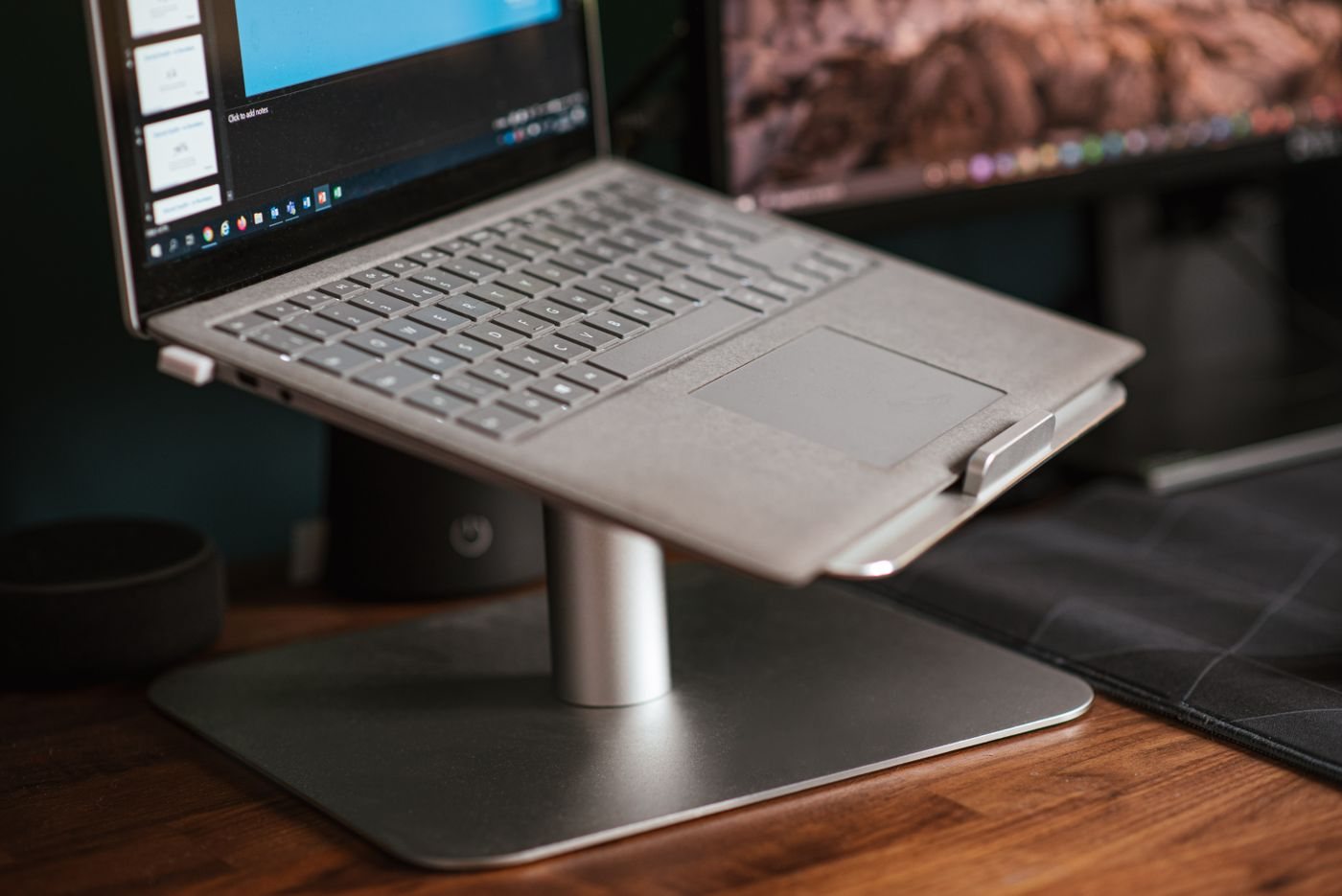 Laptop raised on a stand next to a monitor