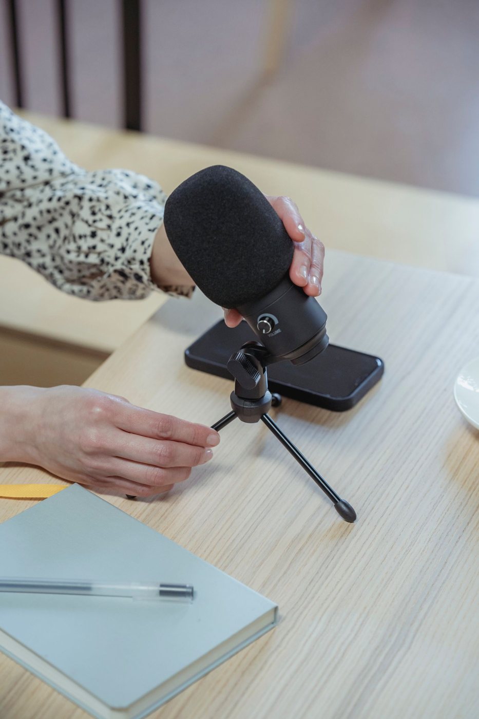Hand positioning a desk microphone beside a notebook