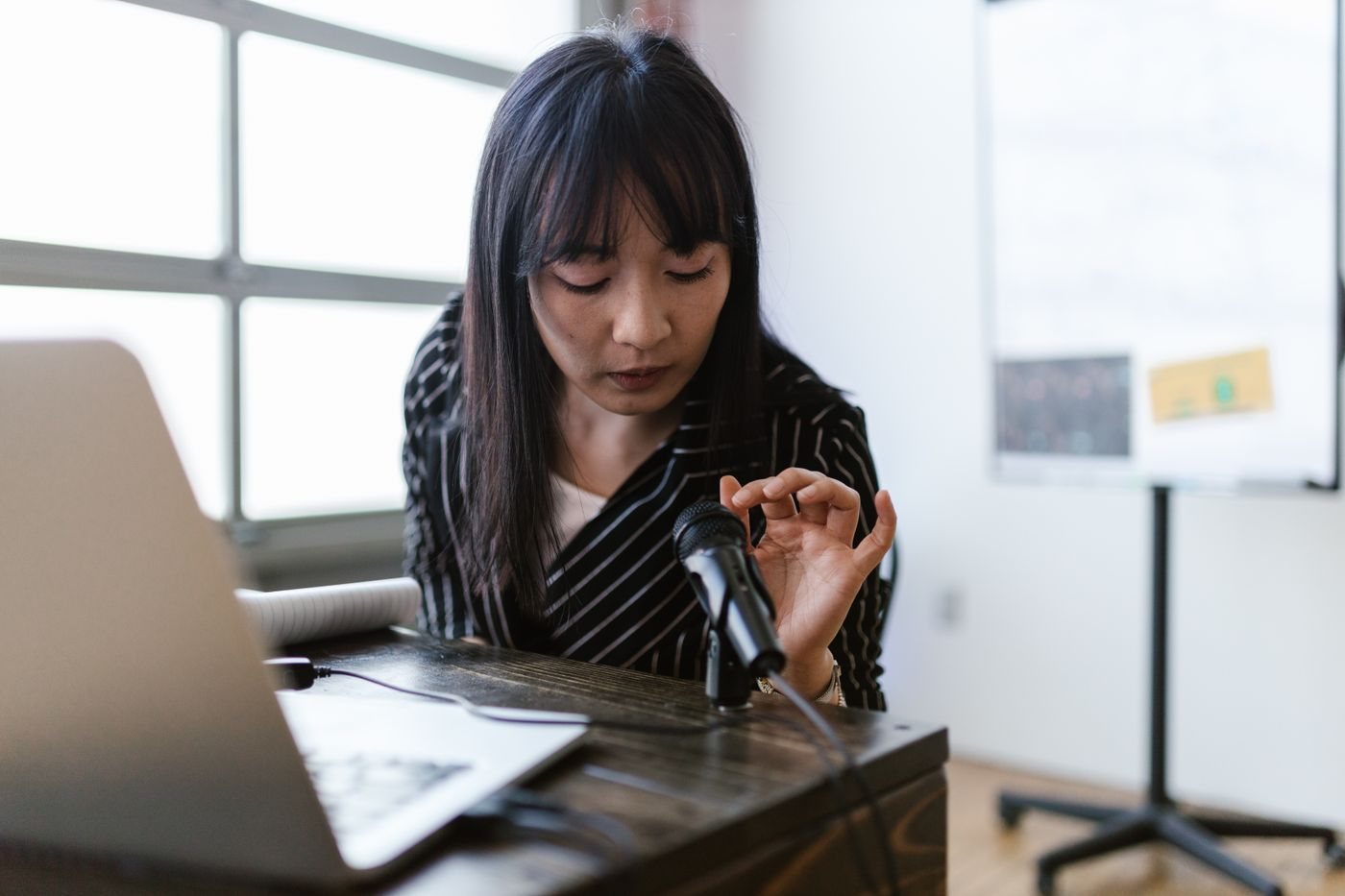Person checking a microphone beside a laptop