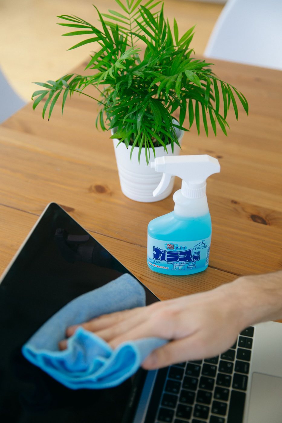 Person wiping a laptop display with a soft cloth