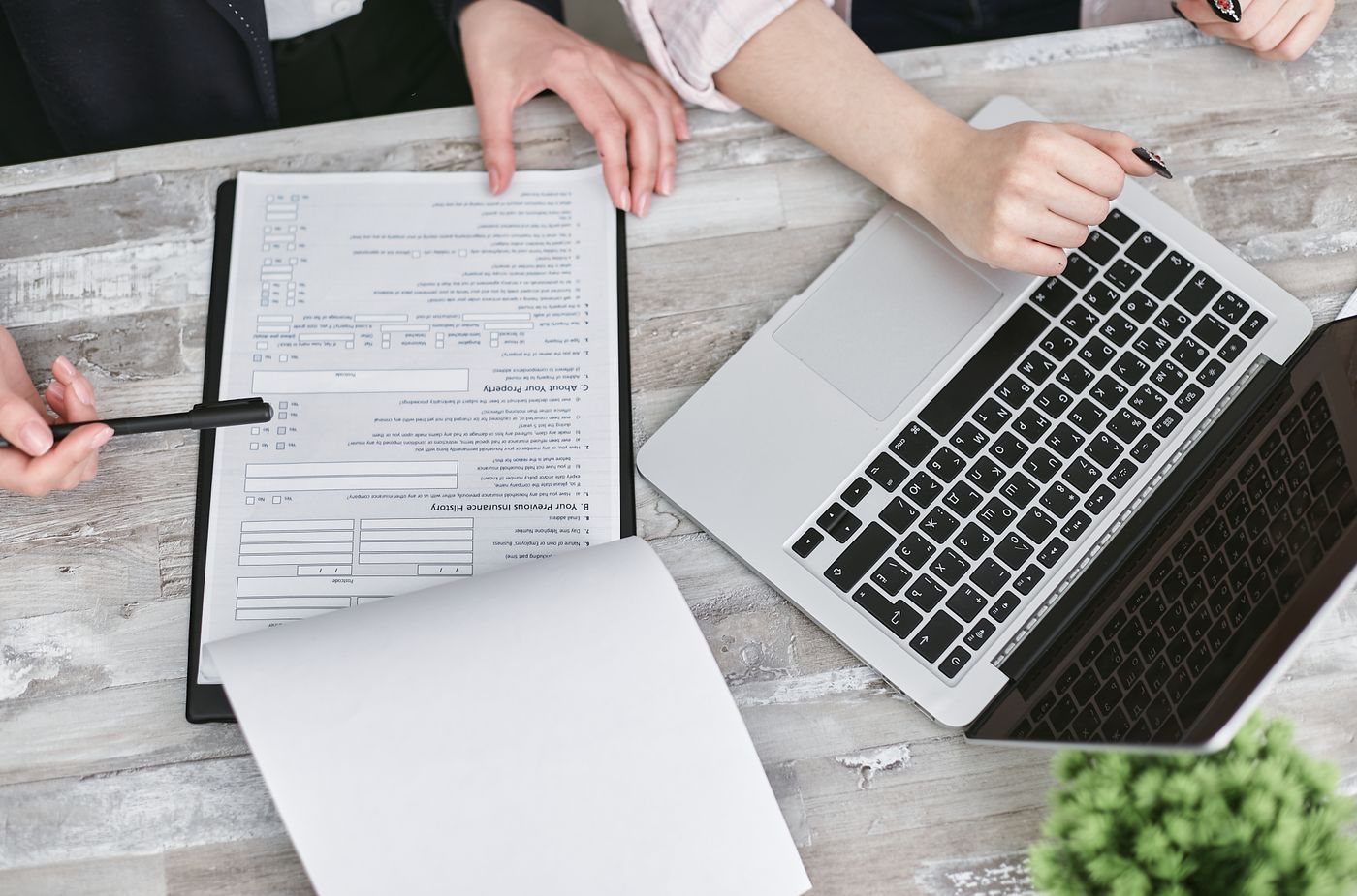 Two people reviewing documents beside a laptop