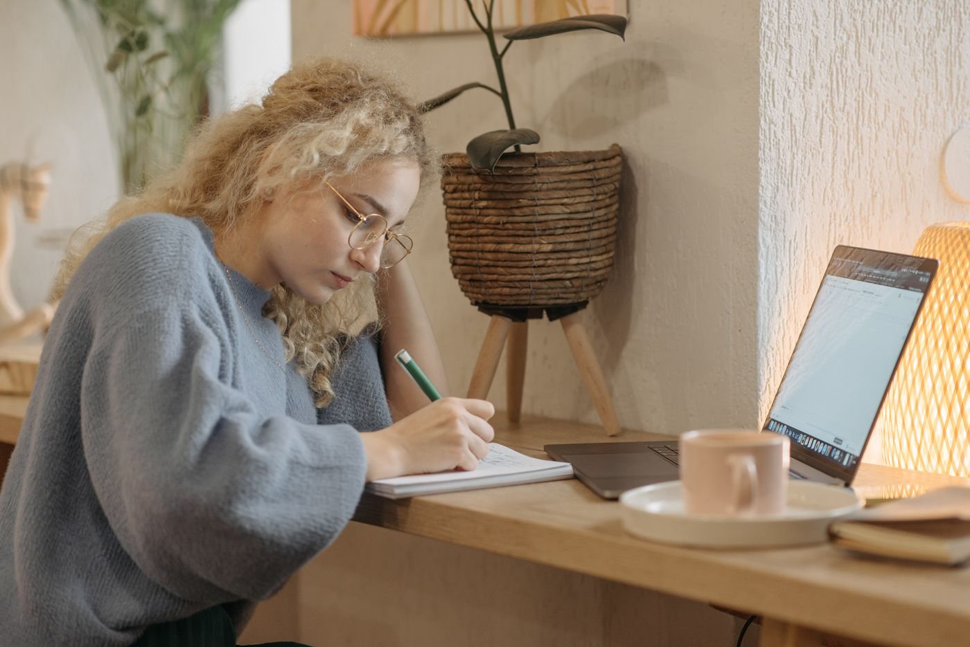 Person recording notes beside a laptop
