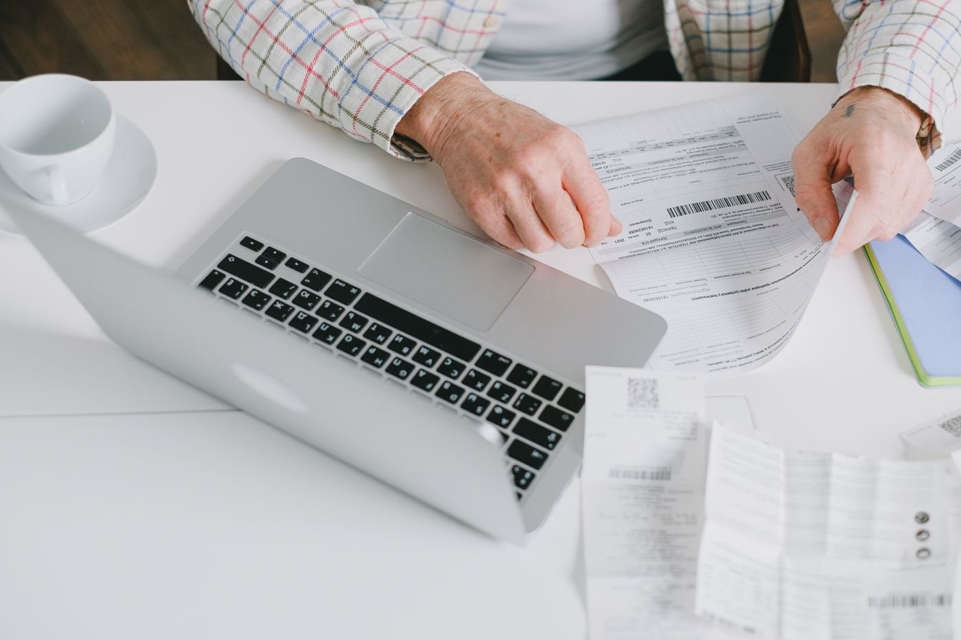 Hands arranging documents beside a laptop